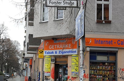 Kiosk  an einer Straßenecke mit orangem Logo und Bannern.