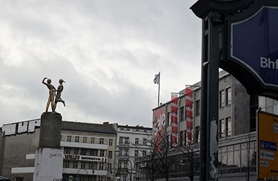 Hermannplatz in Neukölln mit Statur in der Mitte und unter grauem Himmel.