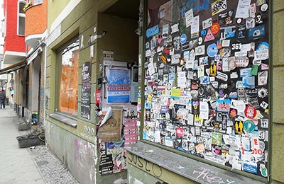 Schaufenster, das von hunderten Sticker übersäht ist, im Reuterkiez.