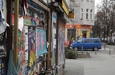 Hauswand, die vollgesprayed und mit Postern beklebt ist.